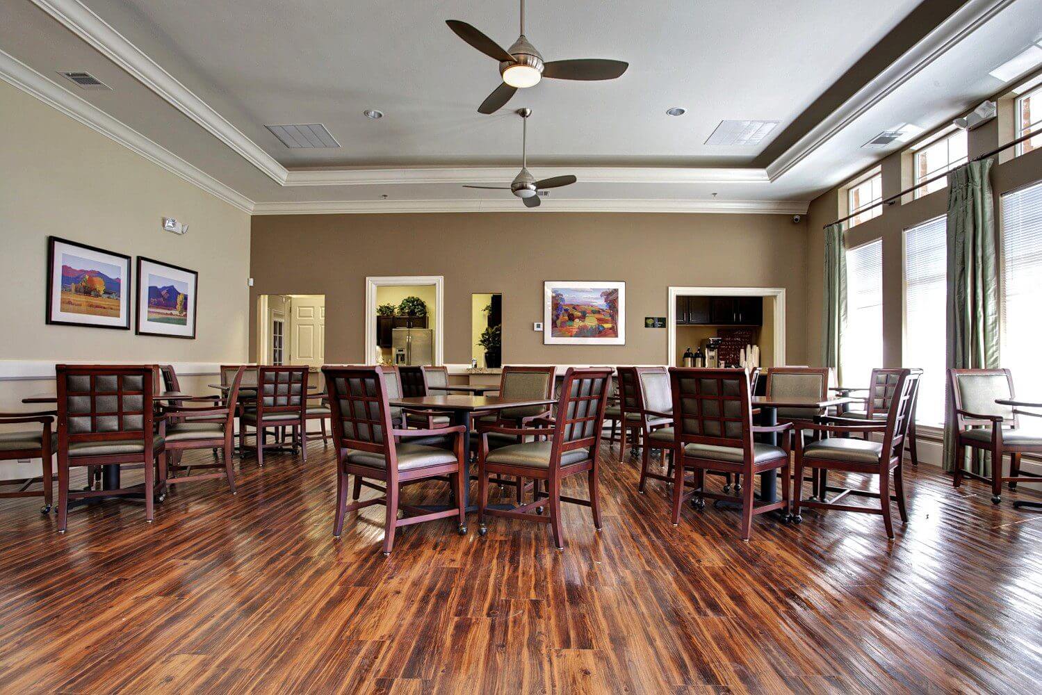 Empty dining room with wooden floors and ceiling fans.