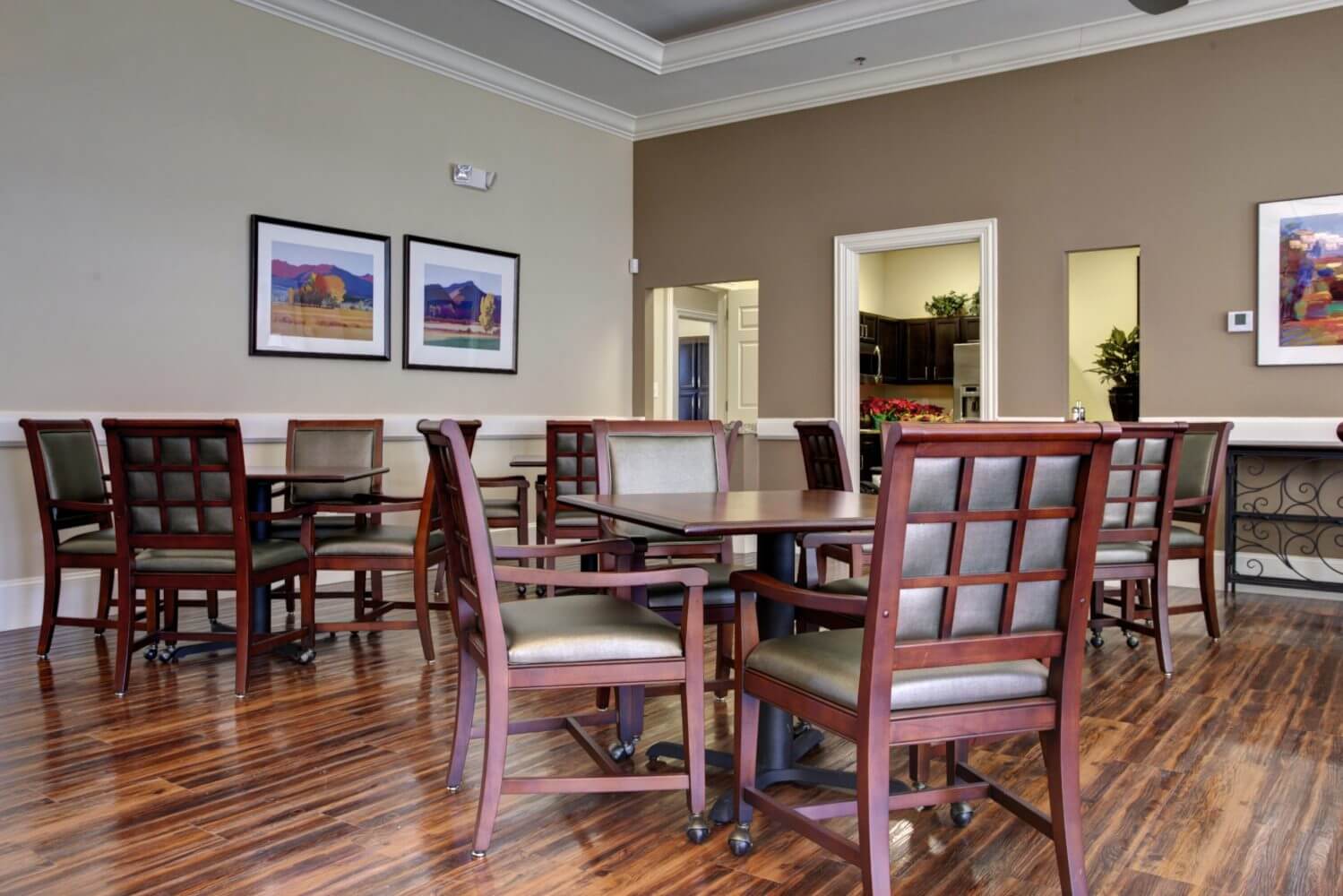 Cozy dining area with wooden chairs and framed artwork on beige walls.