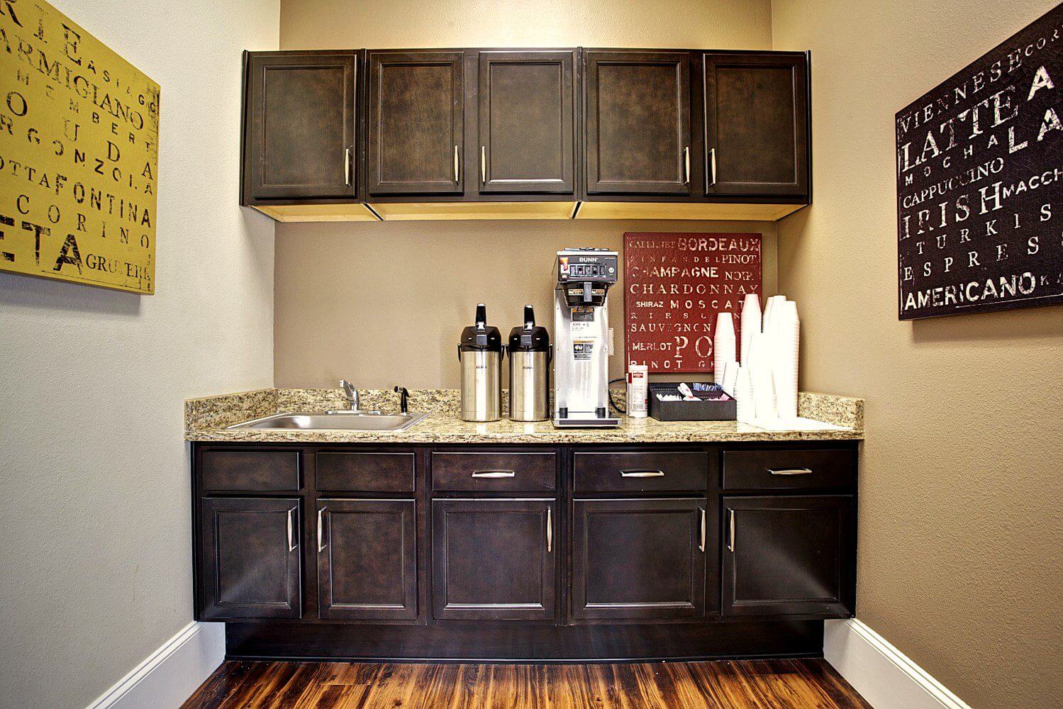 Coffee station with dark cabinets and a granite countertop.