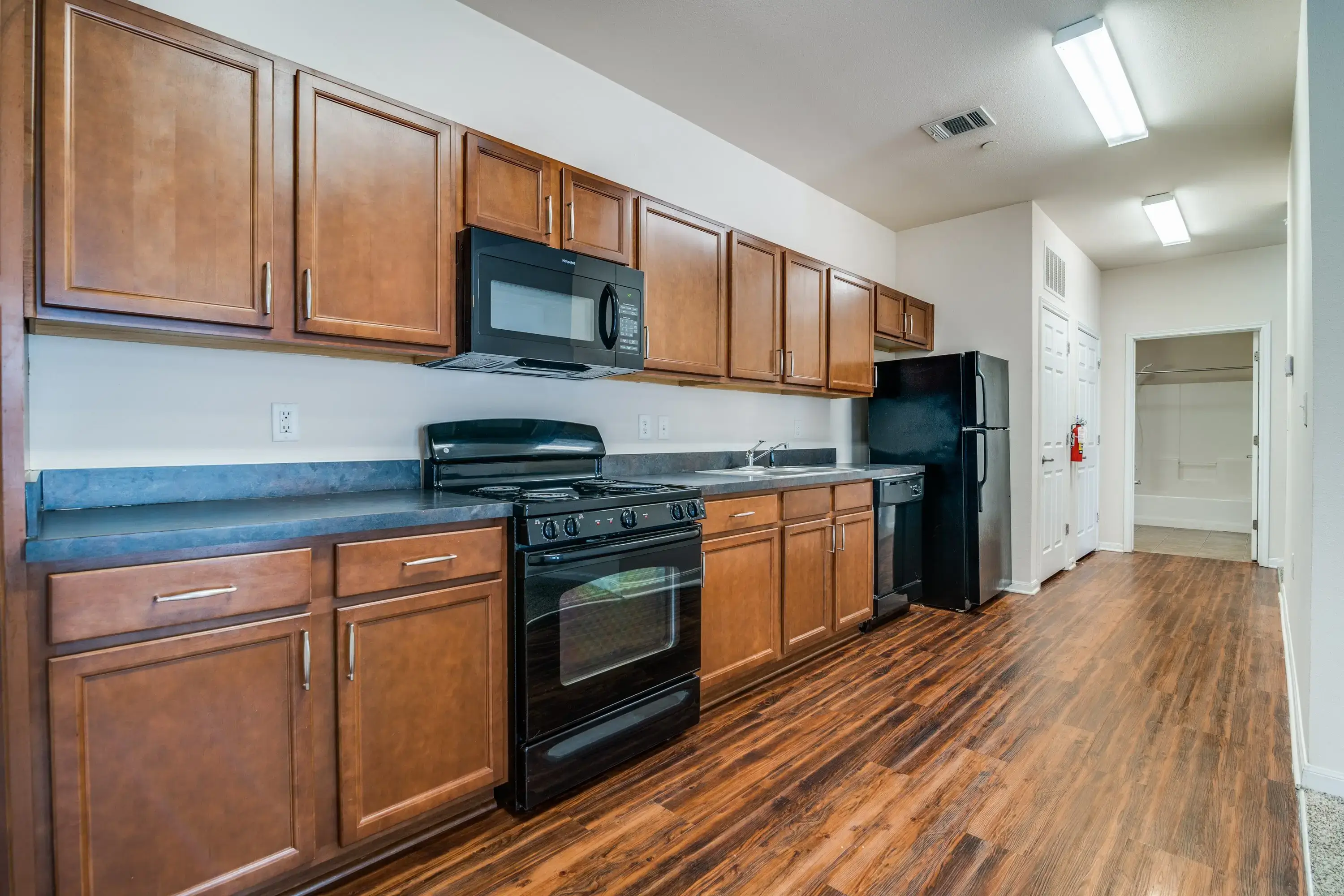 Modern kitchen with wooden cabinets and black appliances.