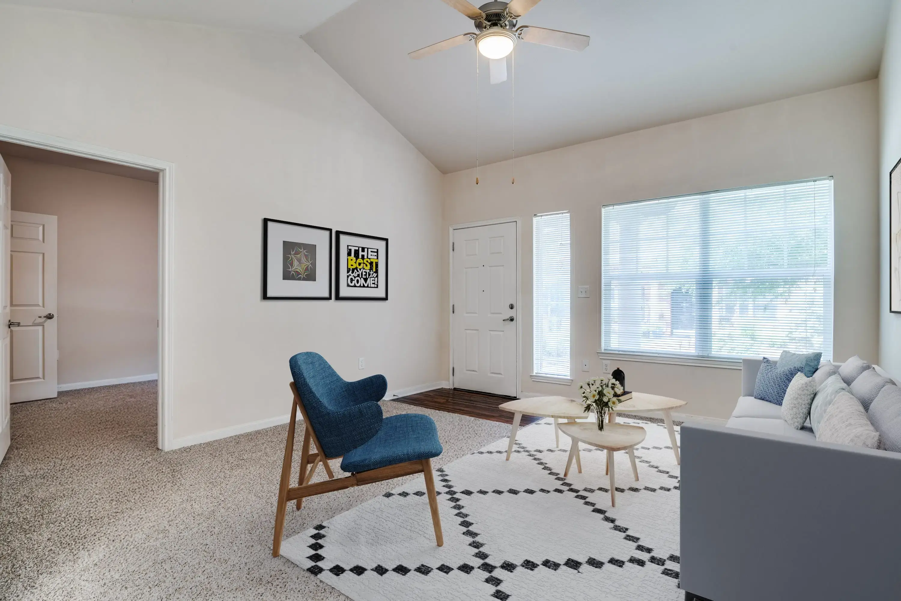 Minimalist room with a blue chair, black-and-white rug, and framed wall art.