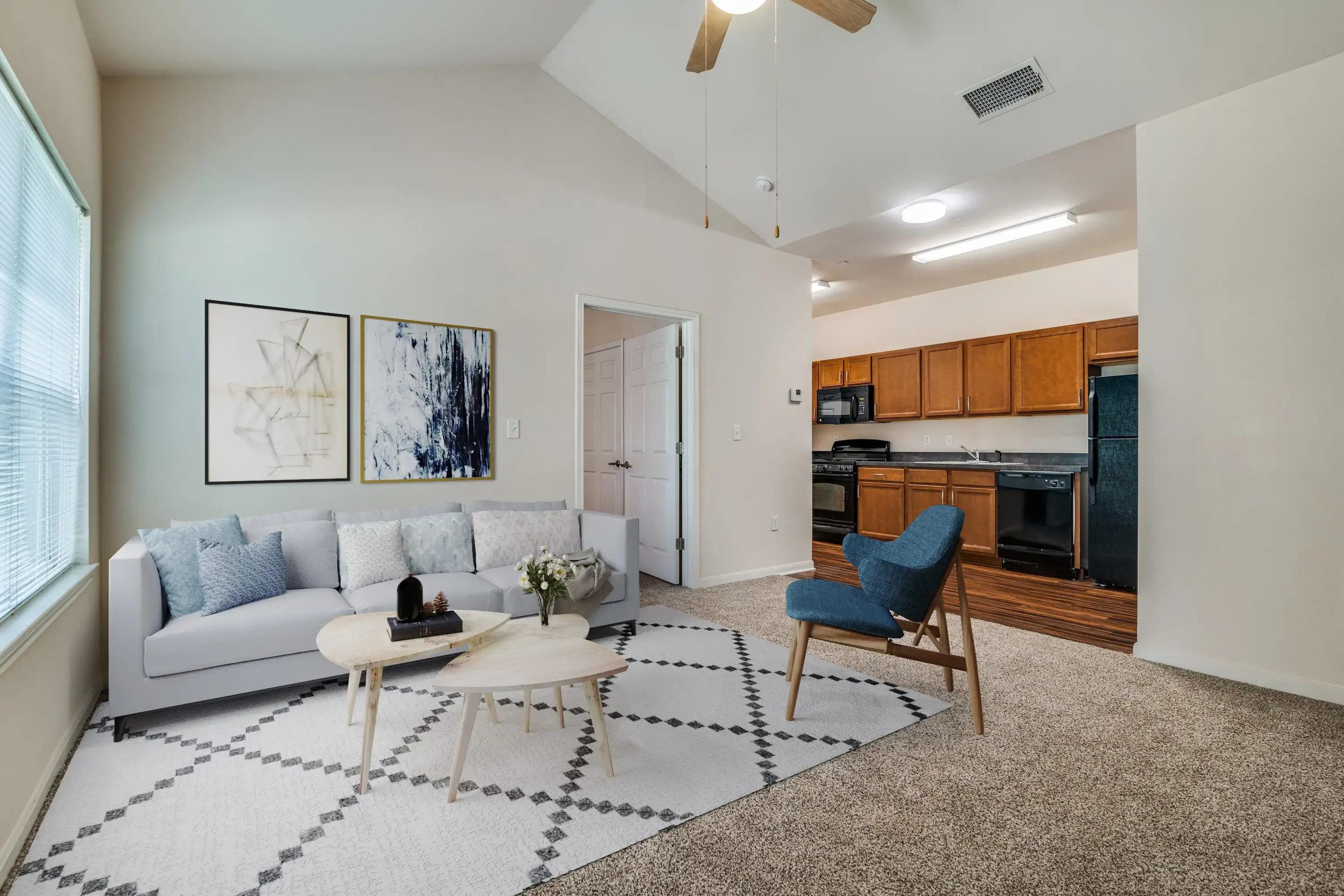 Modern living room with gray sofa, blue chair, and open kitchen.