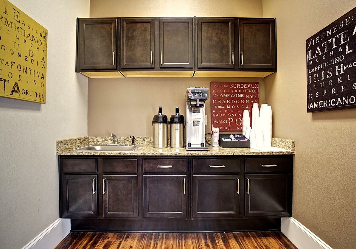 A coffee station with dark cabinets and a granite countertop.