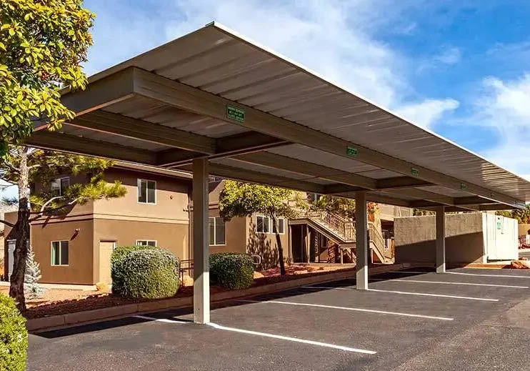 Covered parking spaces with solar panels on the roof under a blue sky.